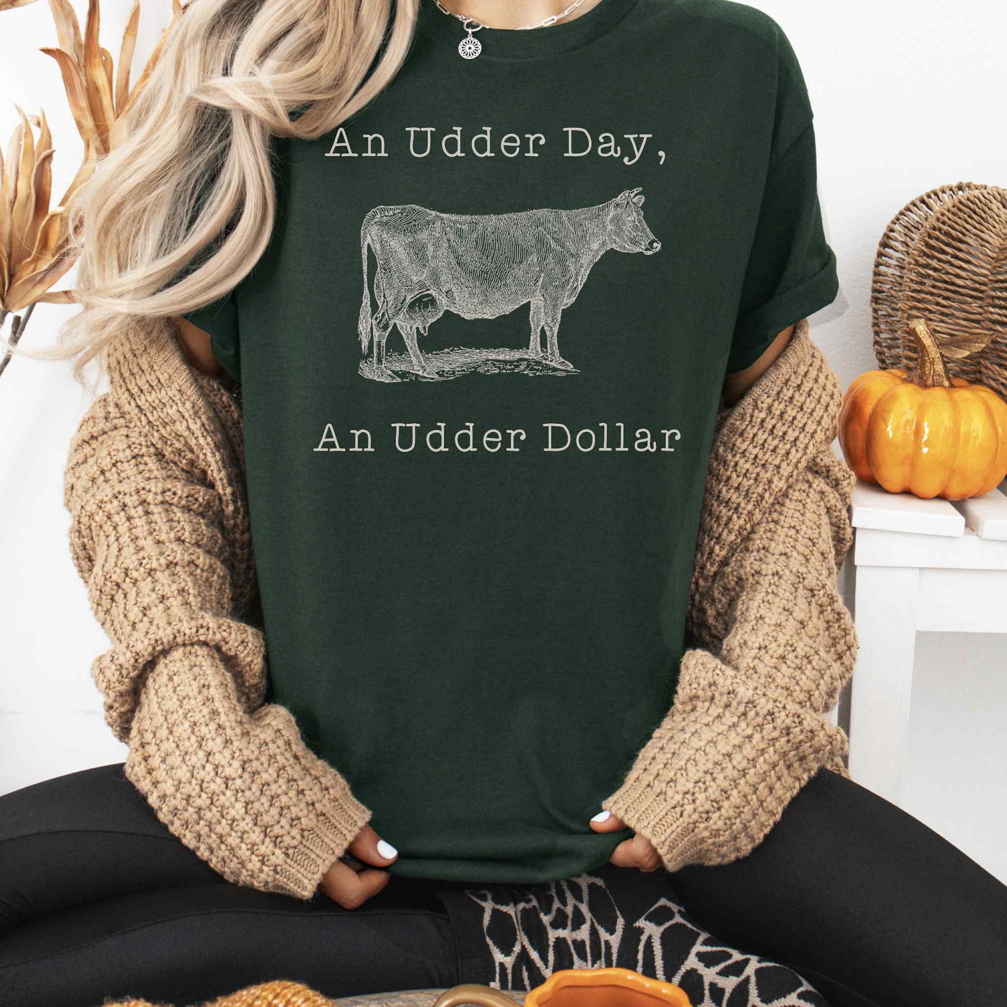 Person wearing a dark green t-shirt with a cow graphic and text, sitting in a cozy indoor setting.
