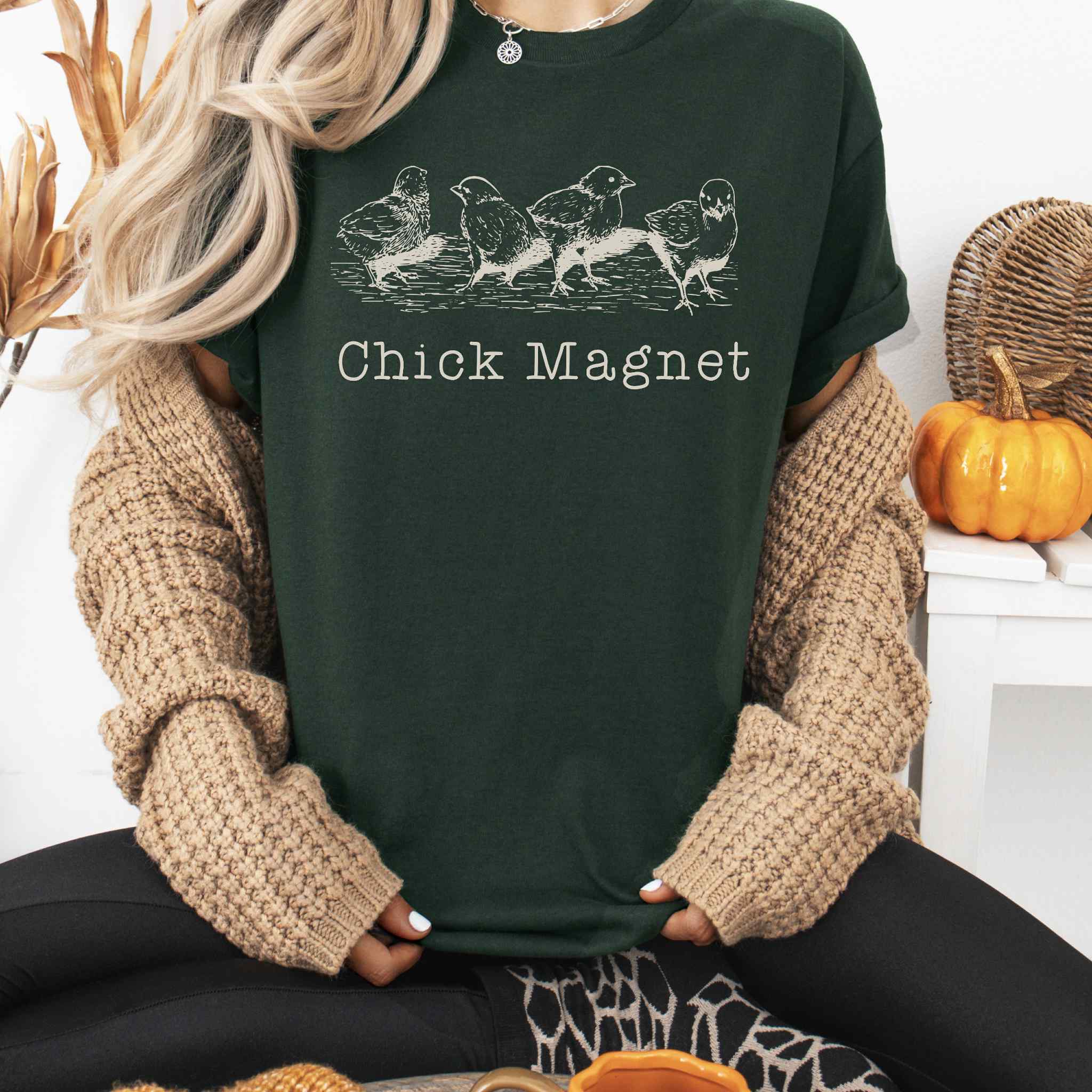 Person wearing a dark green t-shirt with 'Chick Magnet' text and chicken illustrations, sitting in a cozy indoor setting.