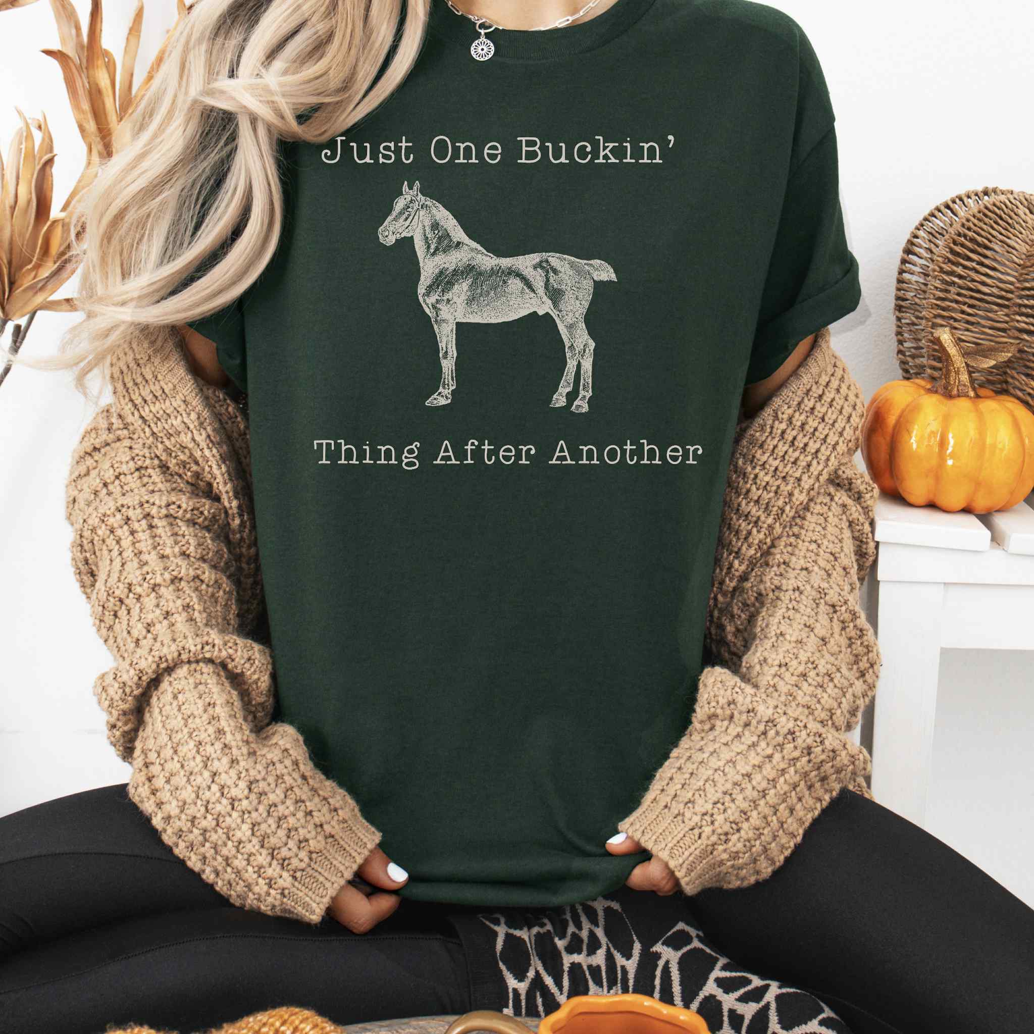 Person wearing a dark green t-shirt with a horse graphic and text, sitting in a cozy indoor setting.