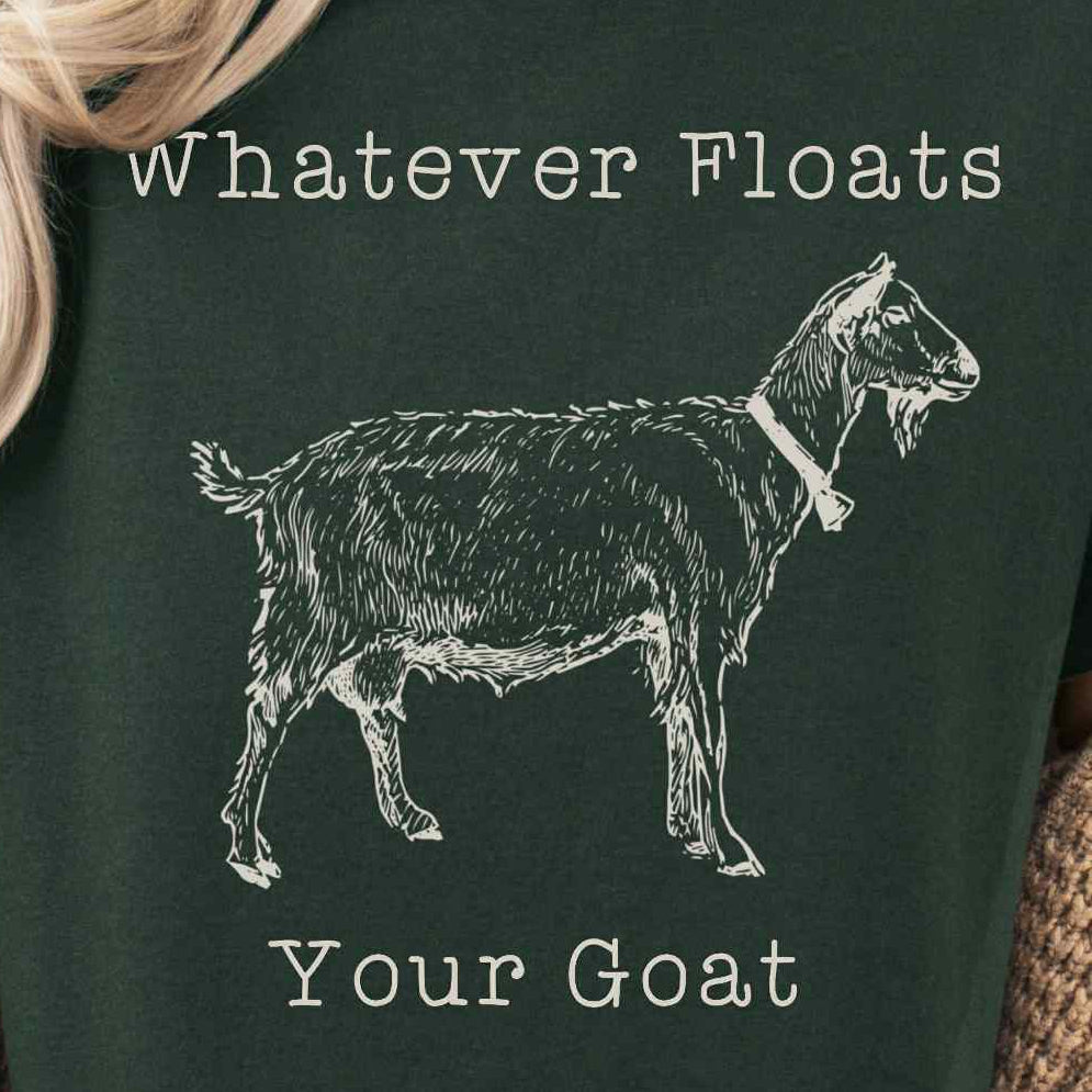 Person wearing a dark green t-shirt with a goat graphic and text, sitting in a cozy indoor setting.