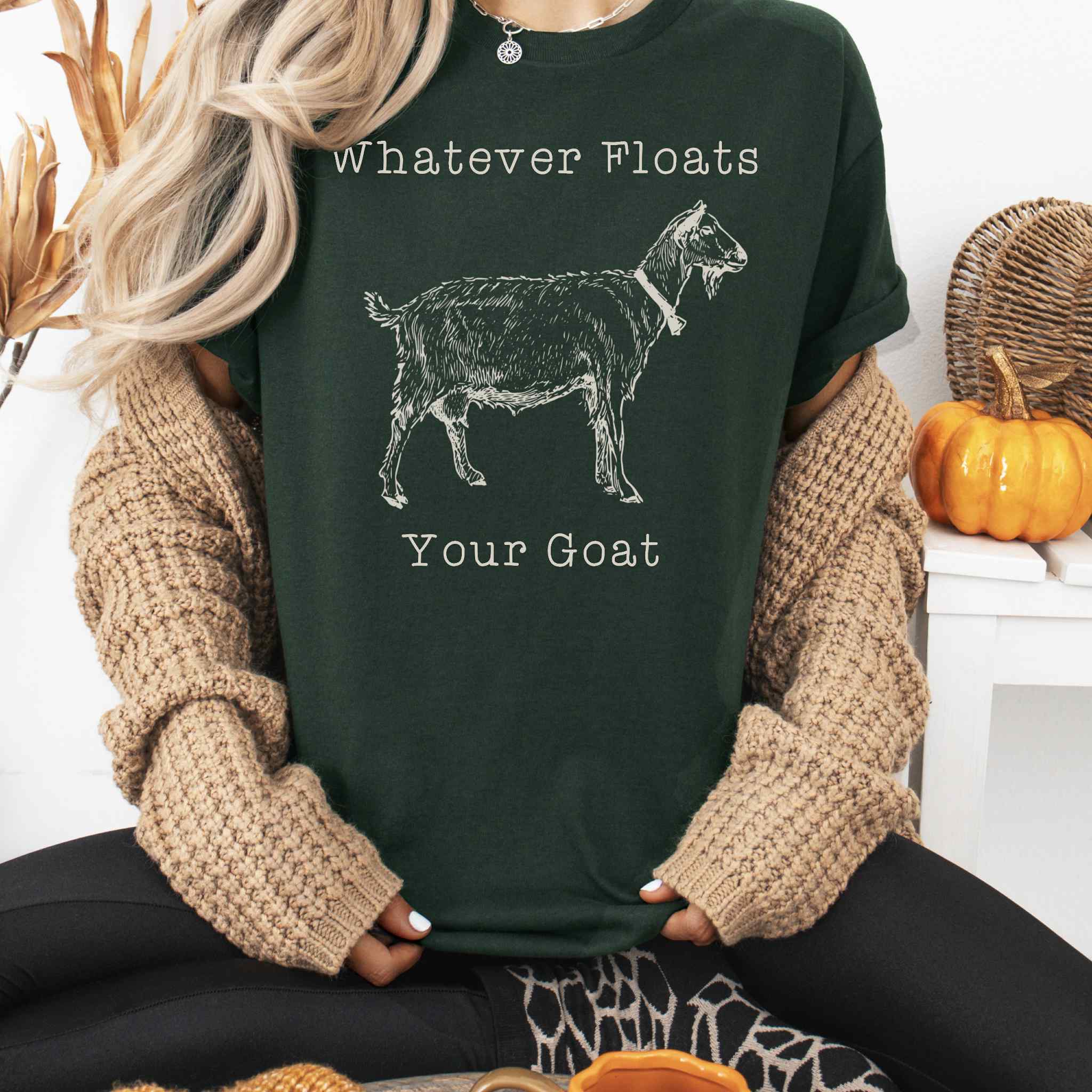 Person wearing a dark green t-shirt with a goat graphic and text, sitting in a cozy indoor setting.