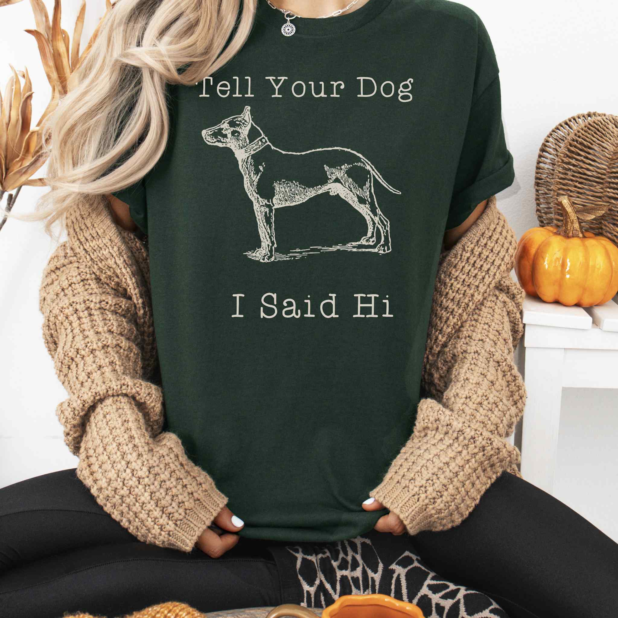 Person wearing a dark green t-shirt with a dog graphic and text, sitting in a cozy indoor setting.